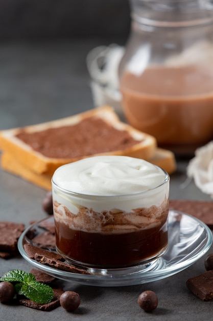 Vaso de leche con chocolate en la superficie oscura.