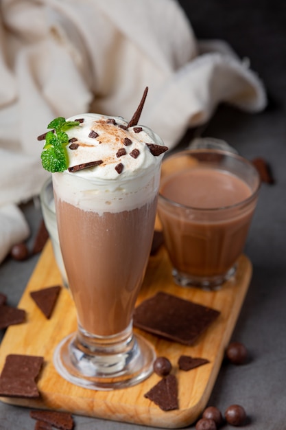 Vaso de leche con chocolate en la superficie oscura.