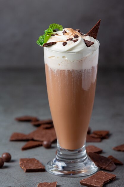 Vaso de leche con chocolate en la superficie oscura.