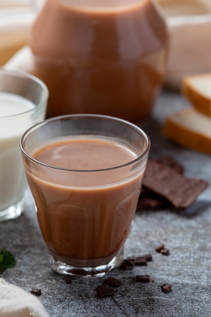 Vaso de leche con chocolate en la superficie oscura.