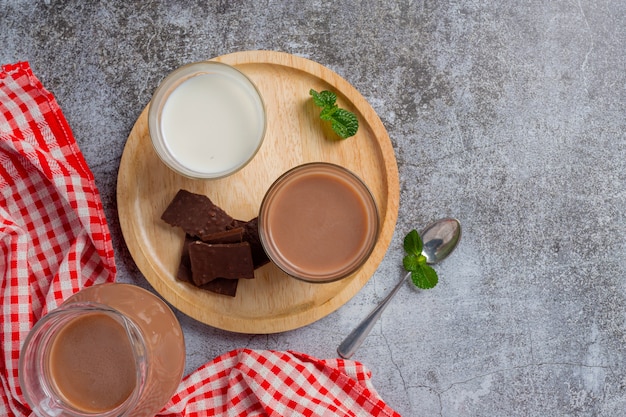 Vaso de leche con chocolate en la superficie oscura.