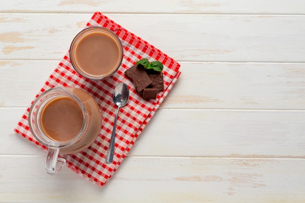 Vaso de leche con chocolate en la superficie oscura.