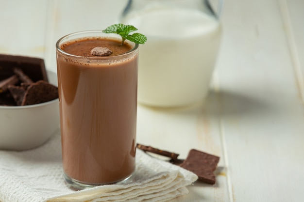 Vaso de leche con chocolate en la superficie oscura.