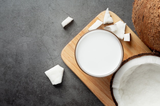 Vaso de leche de coco en tabla de cortar de madera