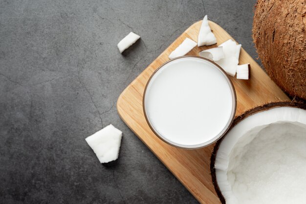 Vaso de leche de coco en tabla de cortar de madera