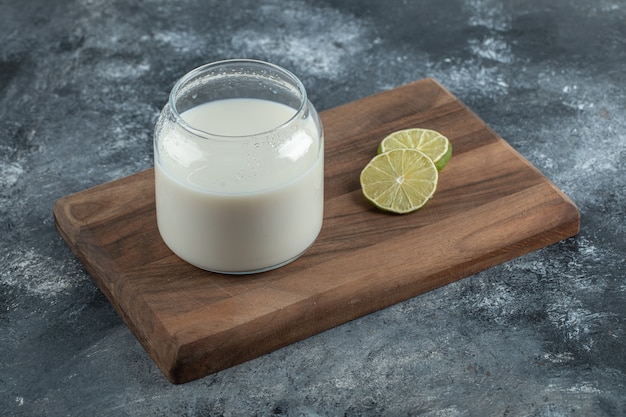 Vaso de leche fresca y rodajas de limón sobre tabla de madera