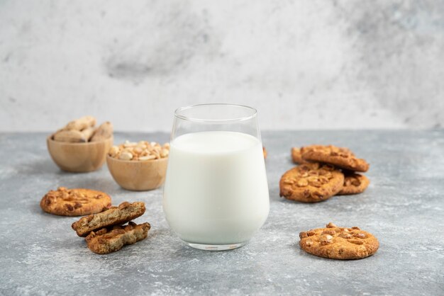 Vaso de leche y galletas caseras con miel sobre mesa de mármol.