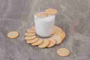 Foto gratuita vaso de leche y galletas redondas sobre superficie de mármol.