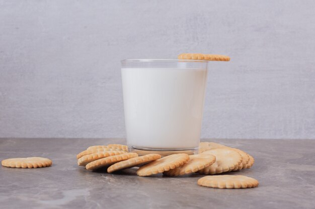 Vaso de leche y mesa de mármol de galletas.