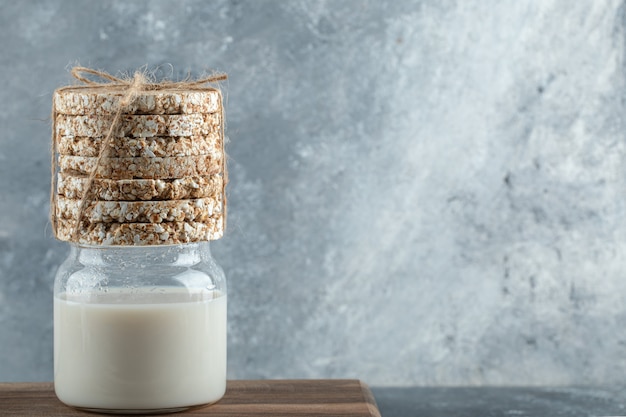 Foto gratuita vaso de leche con pan crujiente sobre plancha de madera