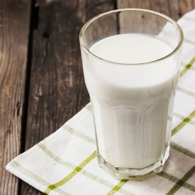 Vaso de leche saludable en blanco servilleta sobre la mesa de madera