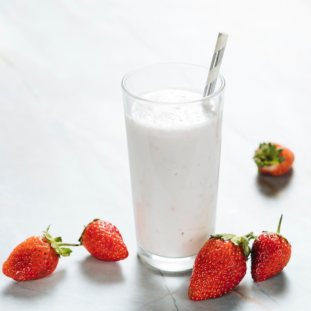 Vaso con leche y stawberries sobre fondo liso