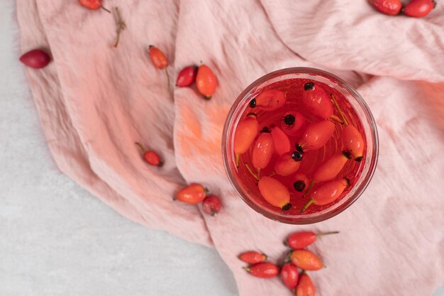 Vaso de limonada fresca con rosa mosqueta sobre tela