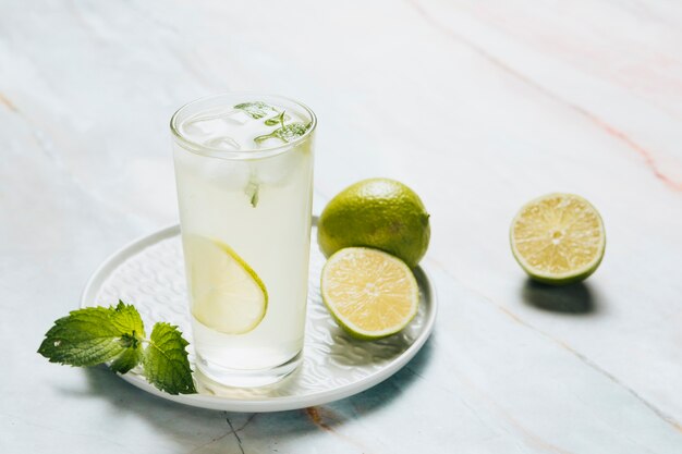 Vaso de limonada y limas sobre fondo de bamble