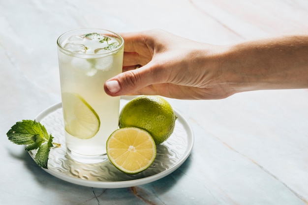 Vaso de limonada y limas sobre fondo de bamble