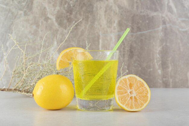 Un vaso de limonada con limón y paja sobre la superficie de mármol