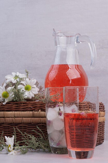 Un vaso de limonada roja con flores en el cuadro blanco.