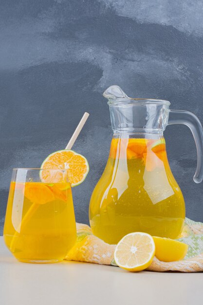 Vaso de limonadas con rodajas de limón en la pared azul.