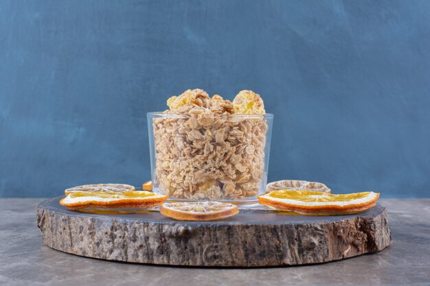 Un vaso lleno de copos de maíz saludables con rodajas de frutos secos de naranja.