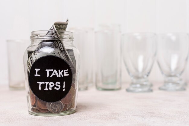 Vaso lleno de dinero y vasos vacíos en el fondo