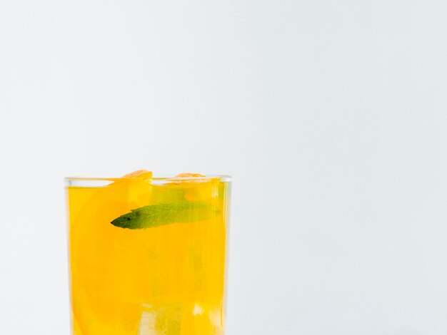 Vaso lleno de jugo de naranja con hielo