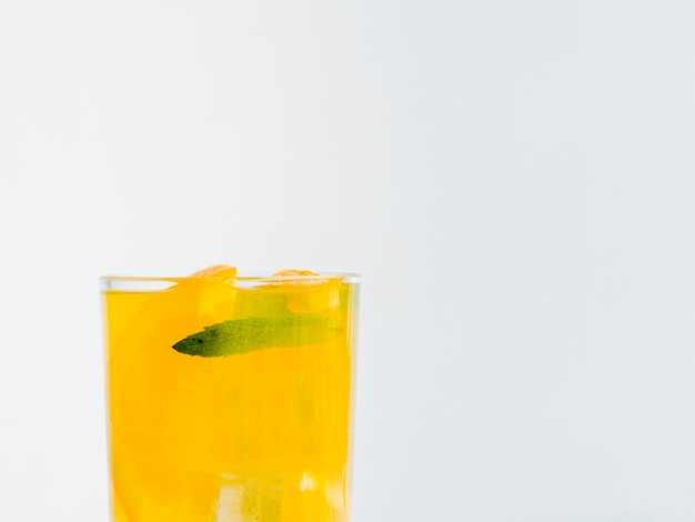 Vaso lleno de jugo de naranja con hielo