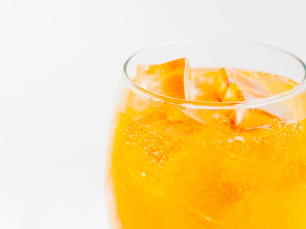 Vaso lleno de refresco de naranja con hielo