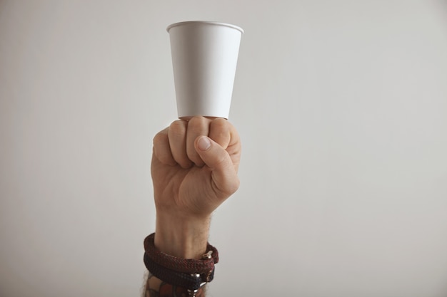 Vaso para llevar en blanco permanecer en puño de hombre brutal, presentación revolucionaria aislada sobre fondo blanco