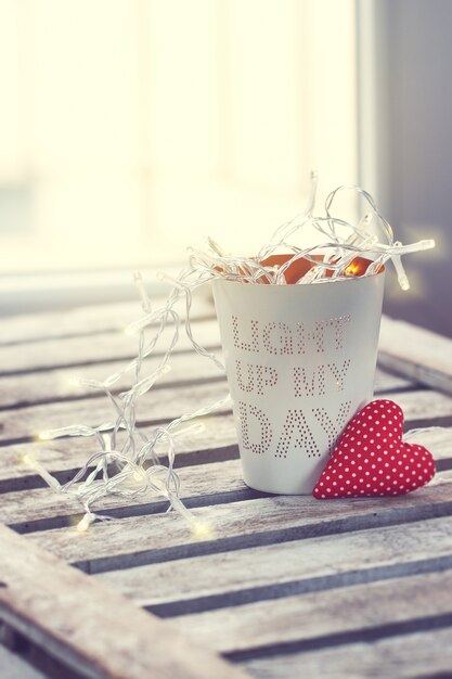 Vaso con mensaje con luces y un corazón al lado