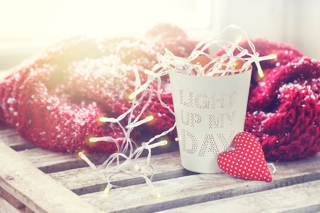 Vaso con mensaje con luces, un corazón y una bufanda con nieve