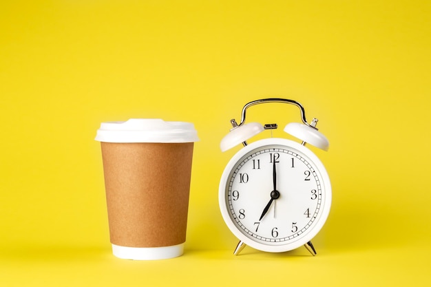 Foto gratuita vaso de papel y despertador sobre fondo amarillo aislado