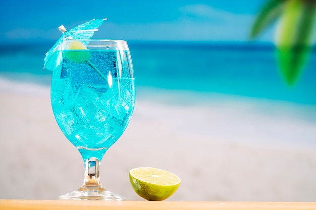 Vaso de refresco bebida azul y rodajas de limón.