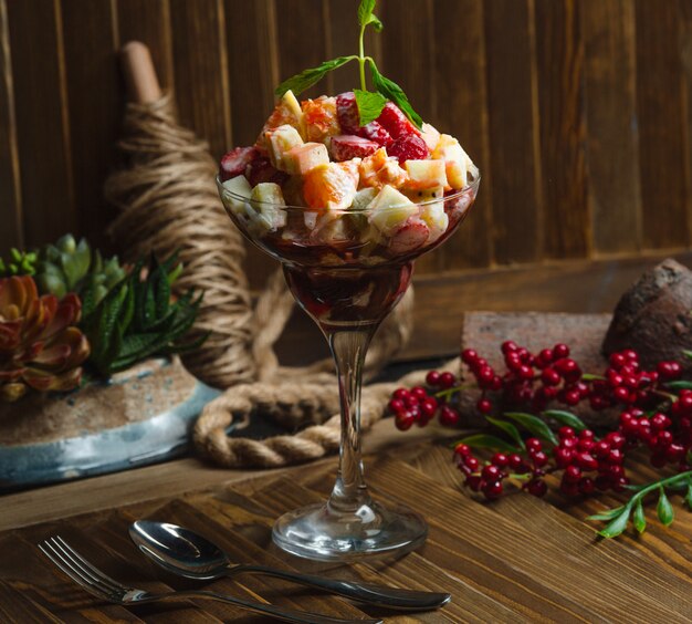 Vaso de rodajas de fruta con salsa cremosa y hojas de menta