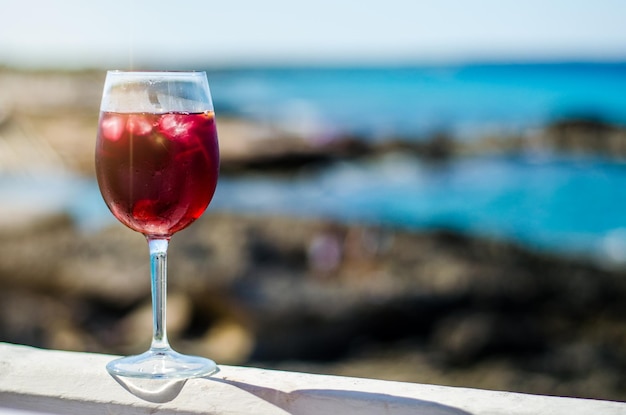 Vaso de sangría junto a un bar de mar