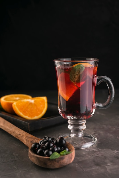 Vaso de té con arándanos y rodajas de naranja