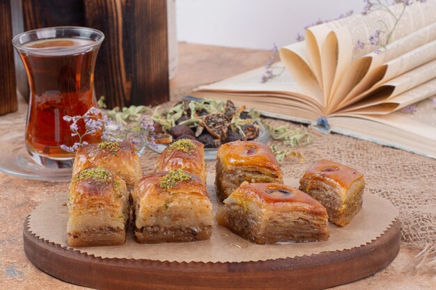 Vaso de té y baklava de pistacho tradicional sobre mesa de mármol.