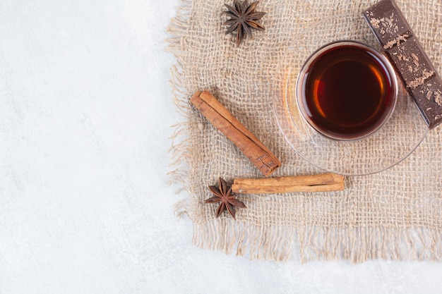 Vaso de té, canela y chocolate sobre arpillera