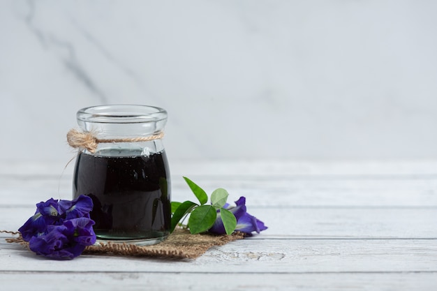 Vaso de té de flor de guisante de mariposa puesto sobre un piso de madera blanca