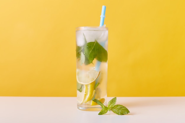 Vaso con té helado con rodajas de limón, menta y cubitos de hielo