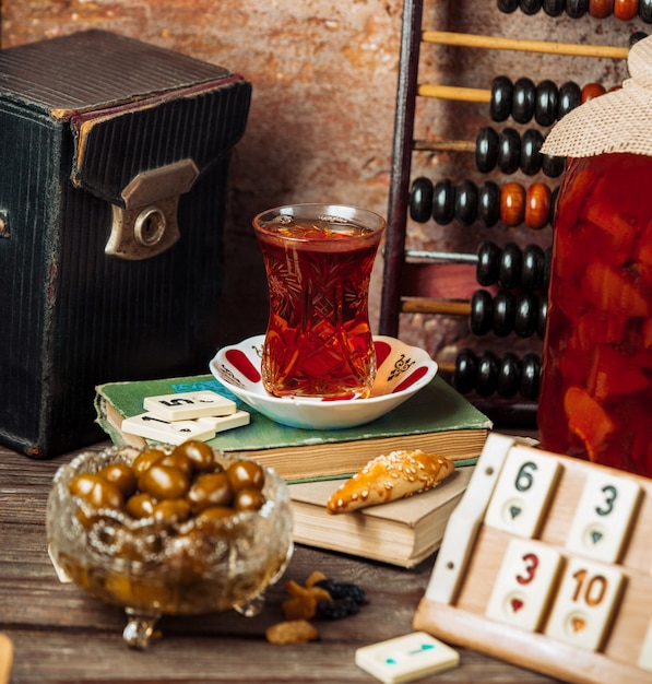 Foto gratuita un vaso de té negro y fechas frescas en una mesa de juego en la tarde.