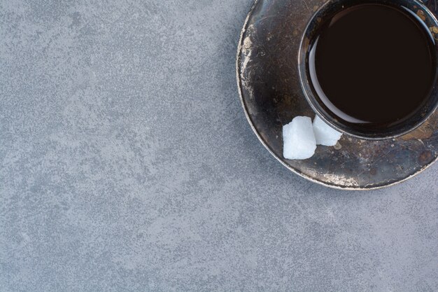 Un vaso de té oscuro de aroma en mesa gris.