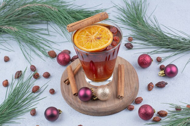 Vaso de té con rosa mosqueta y bolas de Navidad en la superficie.