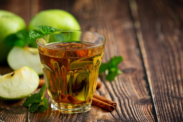 Vaso de té saludable de manzana verde junto a manzanas verdes frescas