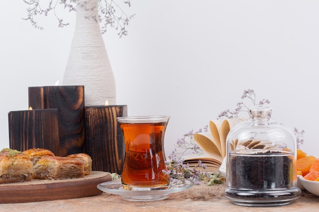 Vaso de té y varios baklavas tradicionales sobre mesa de mármol.