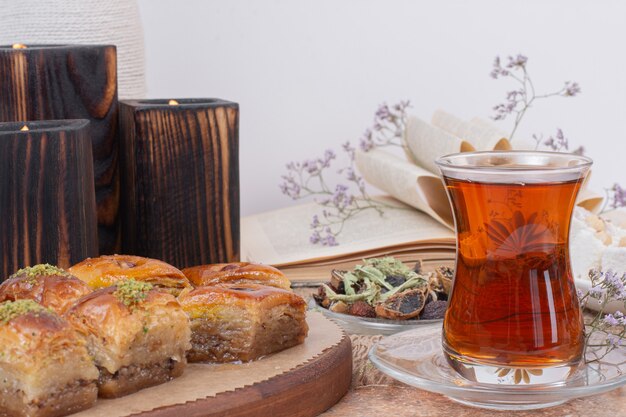 Vaso de té y varios baklavas tradicionales sobre mesa de mármol.