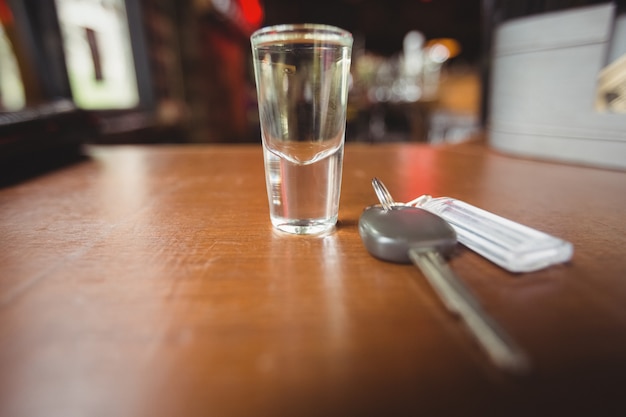 Vaso de tequila con llave del coche en barra de bar