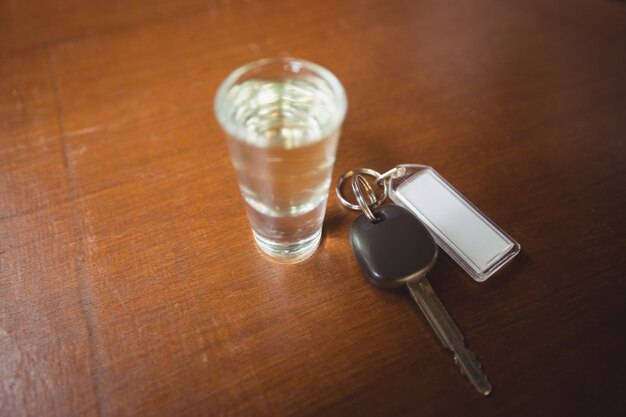 Vaso de tequila con llave del coche en barra de bar