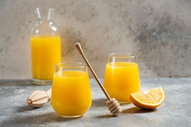 Un vaso de vasos de jugo de naranja y un cucharón de madera.