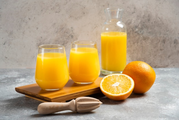 Foto gratuita un vaso de vasos de jugo de naranja y un escariador de madera.