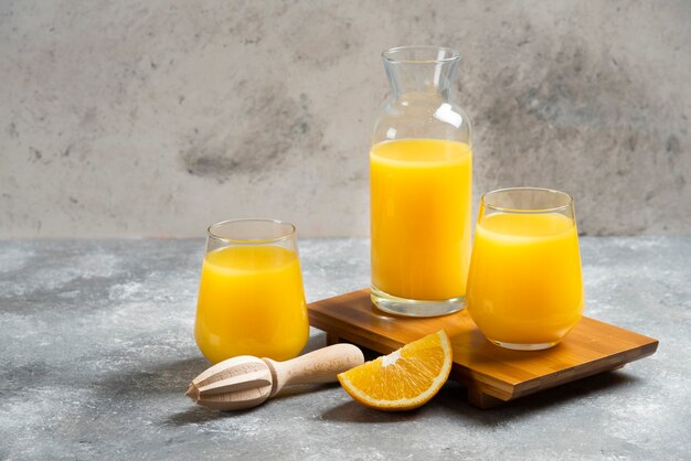 Un vaso de vasos de jugo de naranja y un escariador de madera.